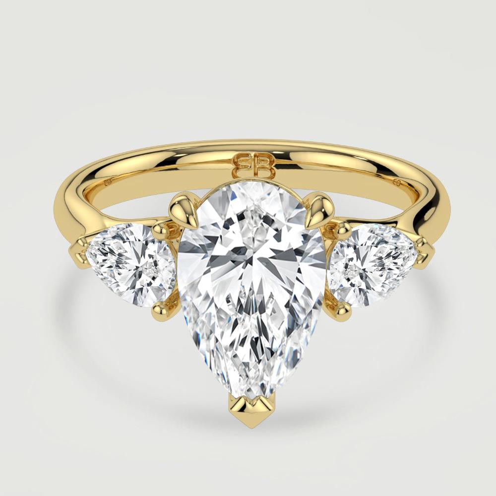 An 18ct yellow gold three stone diamond engagement ring, set with a lab-grown pear shape diamond centre stone held in a three claw setting flanked by a pear shaped lab-grown diamond on either side, held in three claws. Viewed from above.