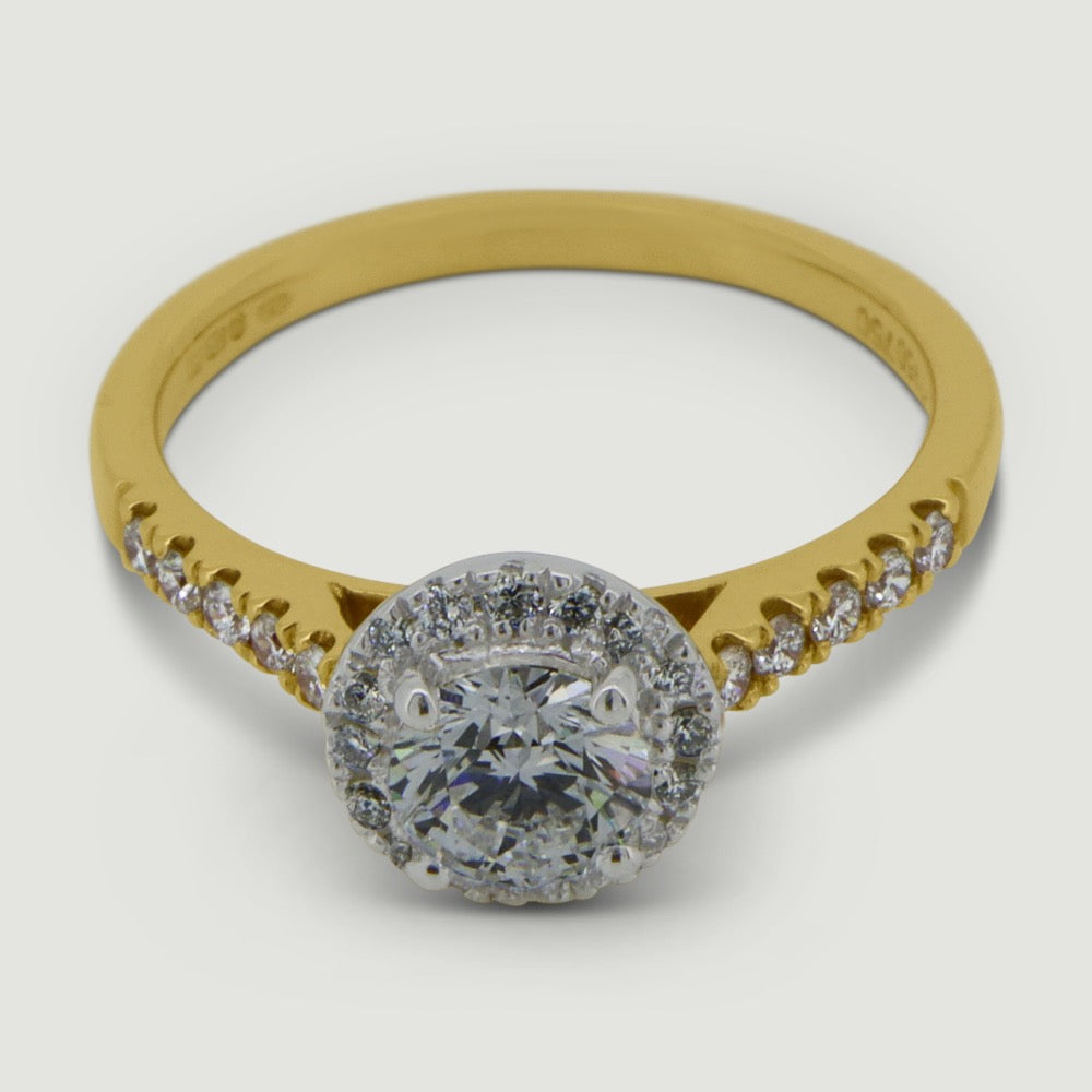 Gold and Platinum halo engagement Ring. The main Round diamond is held in a four claws and is surrounded by a mircro-pavé set halo of diamonds with diamonds micro-pavé set half way down the shoulders - view from an angle