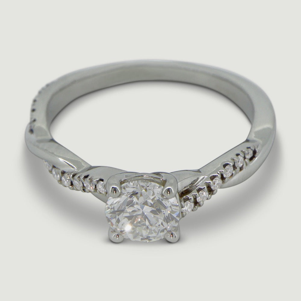 Platinum engagement ring set with a round diamond in a four claw ring mount, the shoulders are plaited with one strand micro-pavé set with diamonds - view from an angle