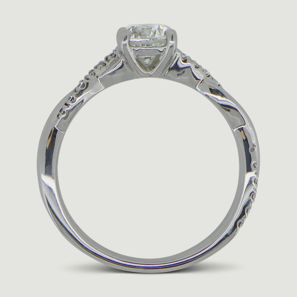 Platinum engagement ring set with a round diamond in a four claw ring mount, the shoulders are plaited with one strand micro-pavé set with diamonds - view from the side