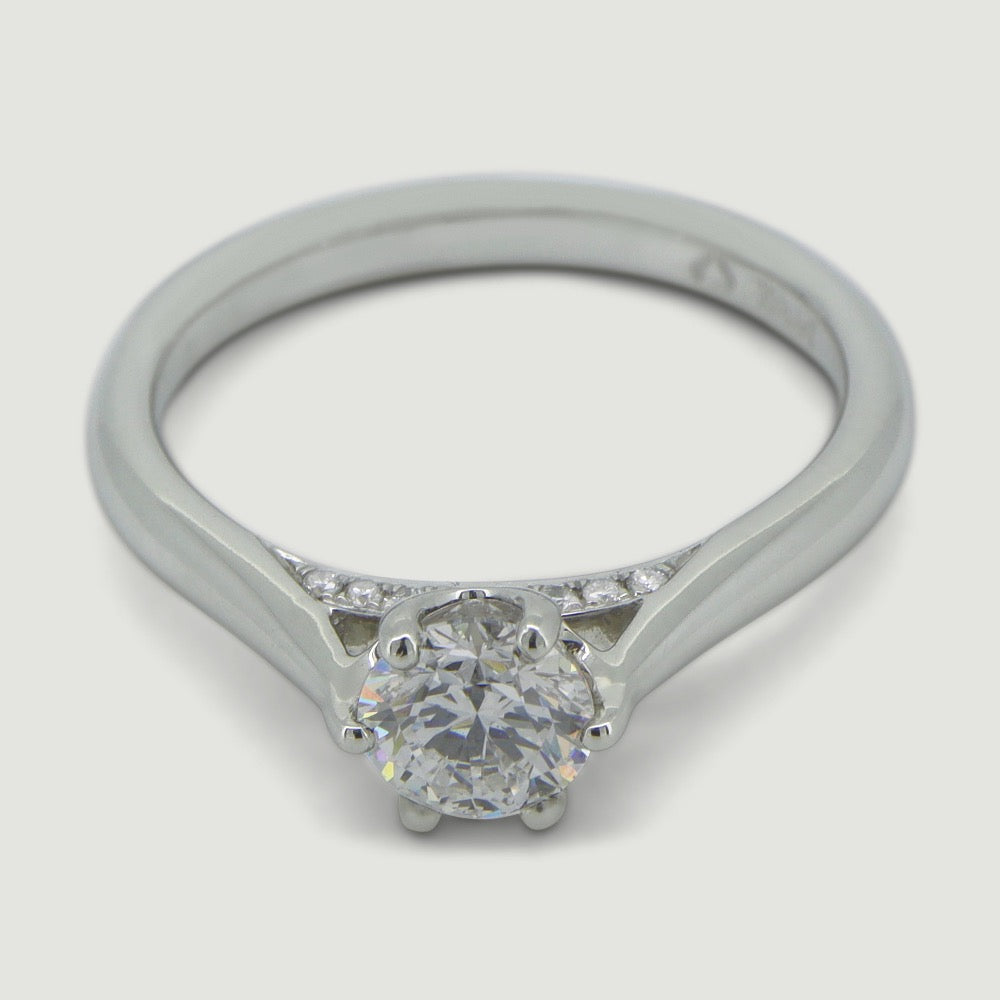 Platinum solitaire engagement Ring. The main Round diamond is held in a six claw crucible setting that sits atop a grain set diamond bridge - view from an angle