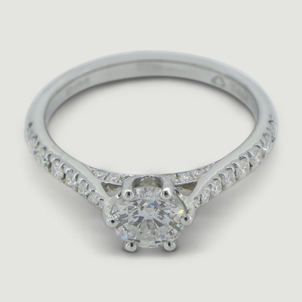 Platinum solitaire engagement Ring. The main Round diamond is held in a six claw crucible setting that sits atop a grain set diamond bridge, the shoulders of the ring are micro-pavé set half way around with round diamonds - view from an angle
