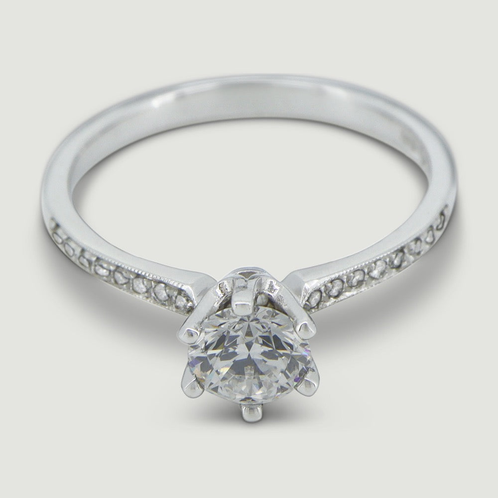 Platinum solitaire engagement Ring. The main Round diamond is held in a six claw Tiffany-style setting with diamonds grain set half way down the shoulders - view from an angle