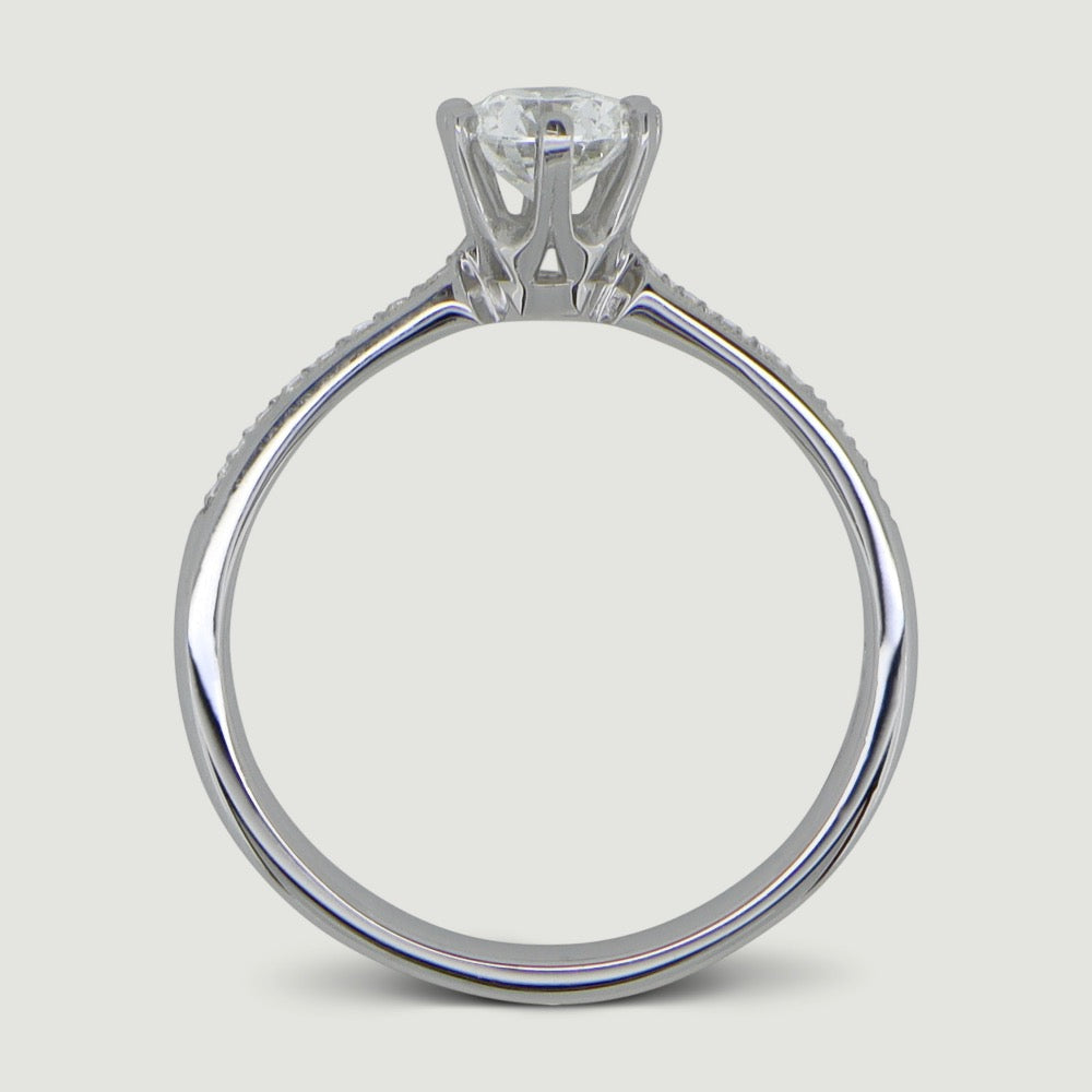 Platinum solitaire engagement Ring. The main Round diamond is held in a six claw Tiffany-style setting with diamonds grain set half way down the shoulders - view from the side