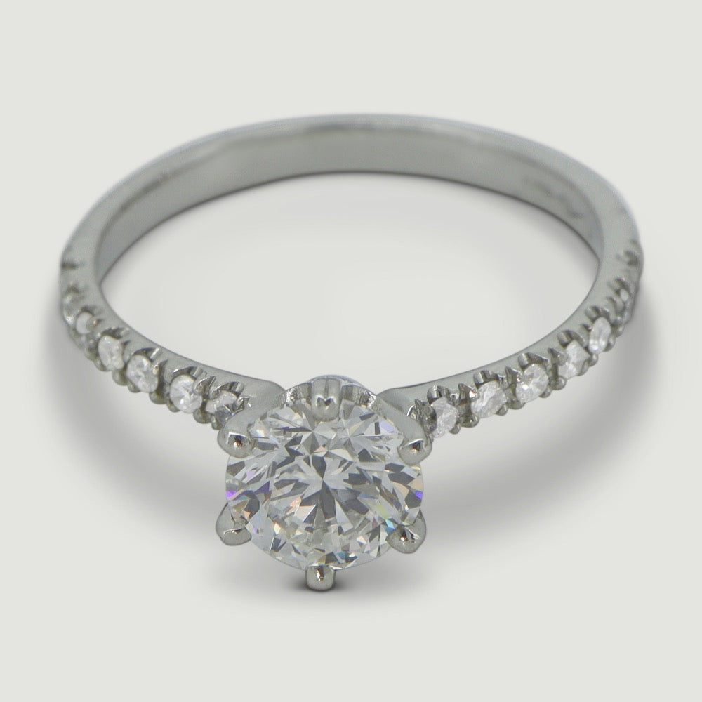 Platinum solitaire engagement Ring. The main Round diamond is held in a six claw Tiffany-style setting with diamonds micro-pavé set half way down the shoulders - view from an angle