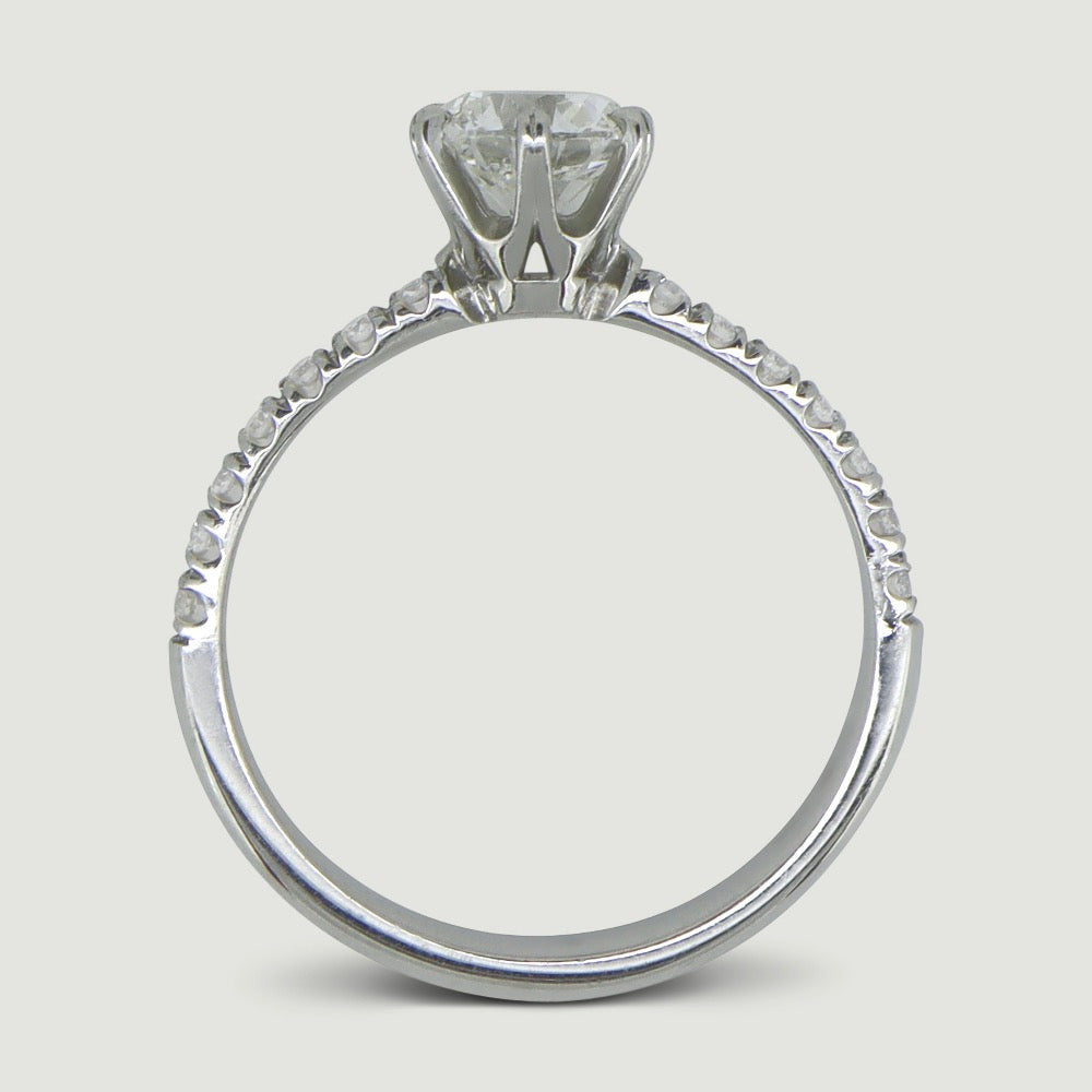 Platinum solitaire engagement Ring. The main Round diamond is held in a six claw Tiffany-style setting with diamonds micro-pavé set half way down the shoulders - view from the side
