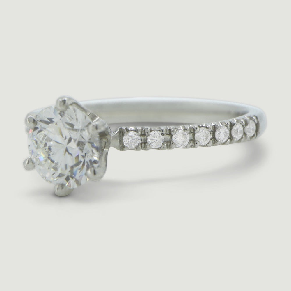 Platinum solitaire engagement Ring. The main Round diamond is held in a six claw Tiffany-style setting with diamonds micro-pavé set half way down the shoulders - focus on the shoulders