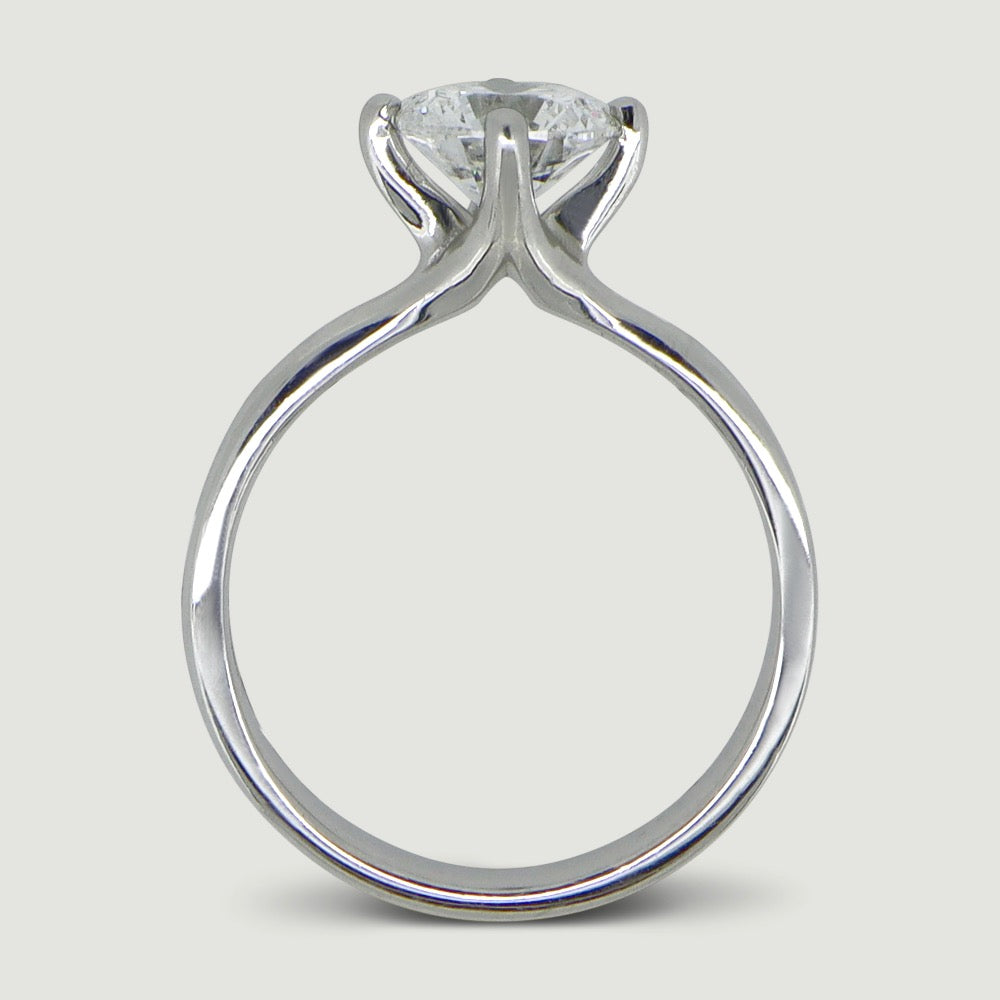 Platinum solitaire engagement Ring. The main Round diamond is held in a four claw compass setting - view from the side