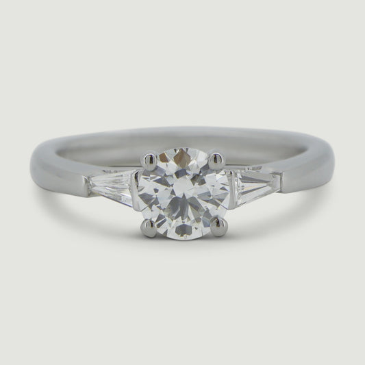 Platinum Ring set with three diamonds. The main Round diamond is held in four claws and the two flanking tapered baguette cut. diamonds are set into the shoulders - view from the top
